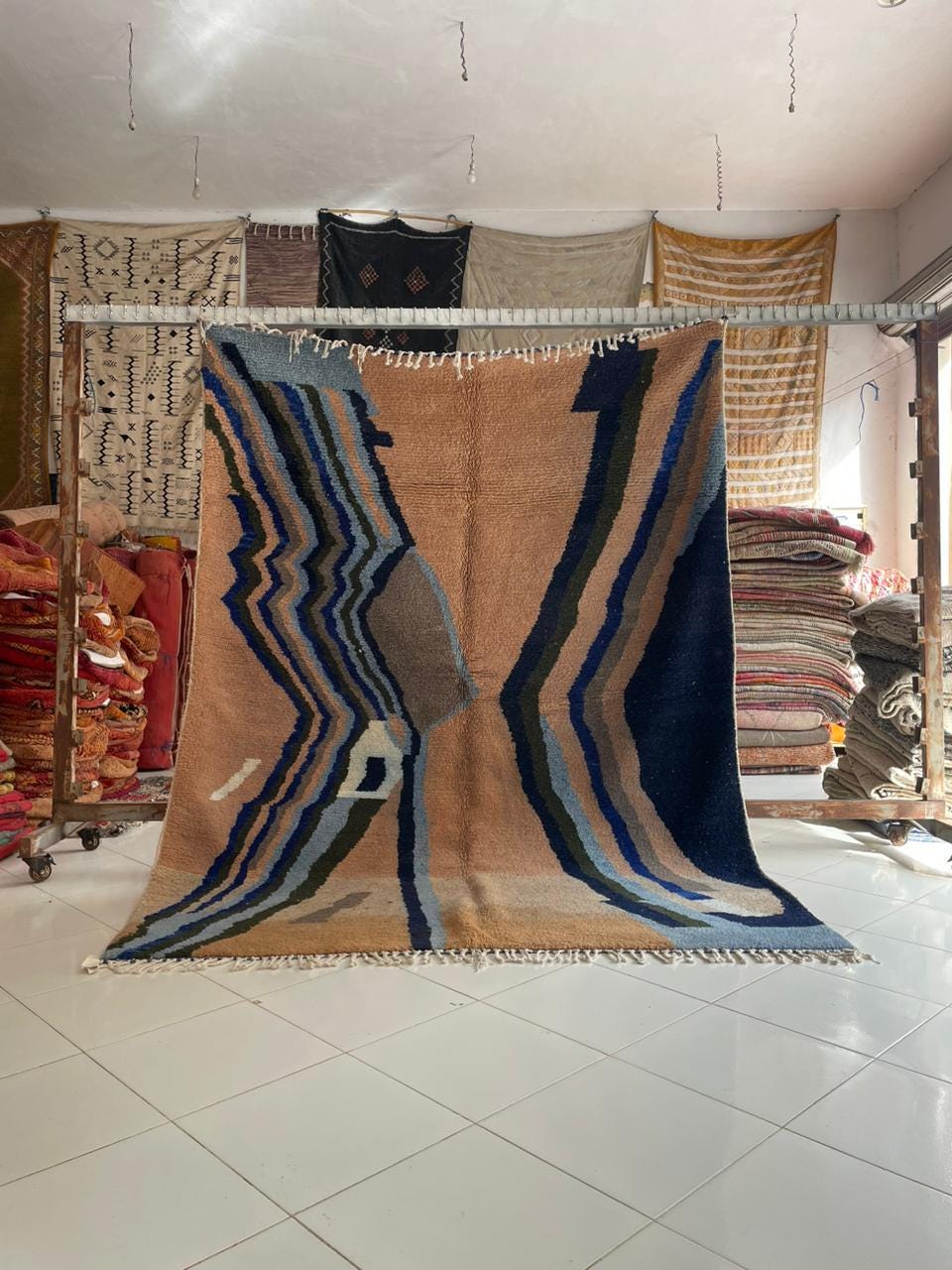 Lifestyle shot of a colorful Moroccan rug featuring geometric patterns in beige, blue, and green.