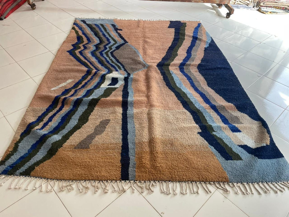 Top view of a colorful Moroccan rug showcasing geometric patterns in beige, blue, and green.