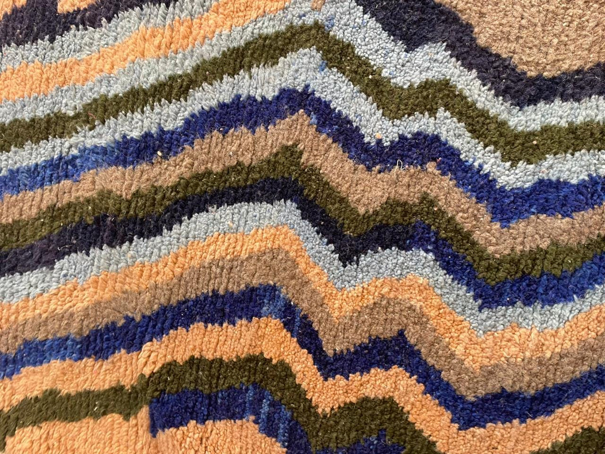 Close-up detail of a colorful Moroccan rug featuring a textured surface with zigzag patterns.