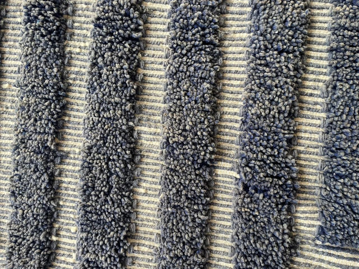 Detail close-up of a gray Moroccan rug featuring geometric lines and a textured surface.