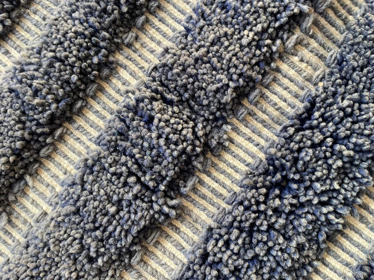 Detail close-up of a gray Moroccan rug showcasing a striped pattern and textured surface.