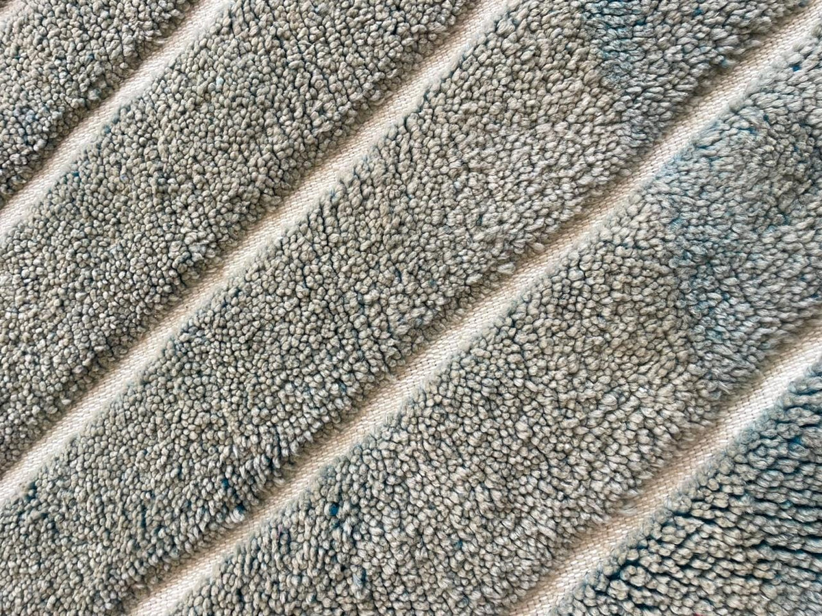 Detail shot of a gray Moroccan rug with a striped pattern against a contrasting background.