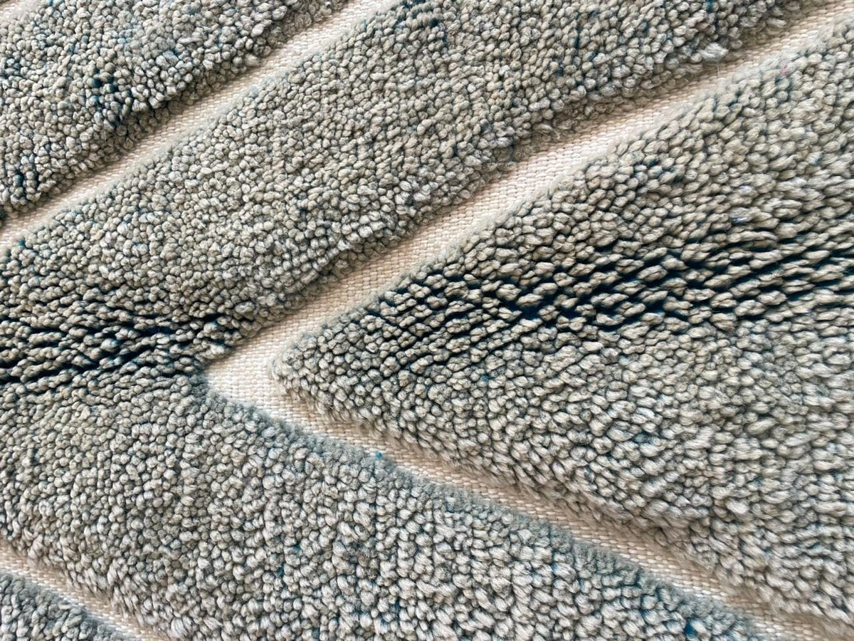 Detail shot of a gray Moroccan rug featuring a textured surface and striped pattern.