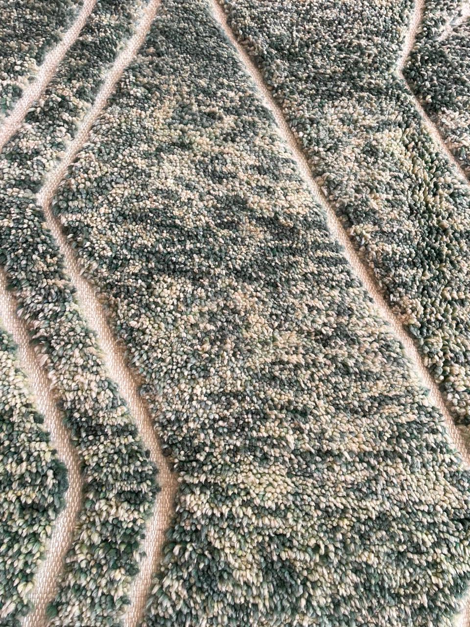 Close-up detail of a green Moroccan rug with a geometric design.
