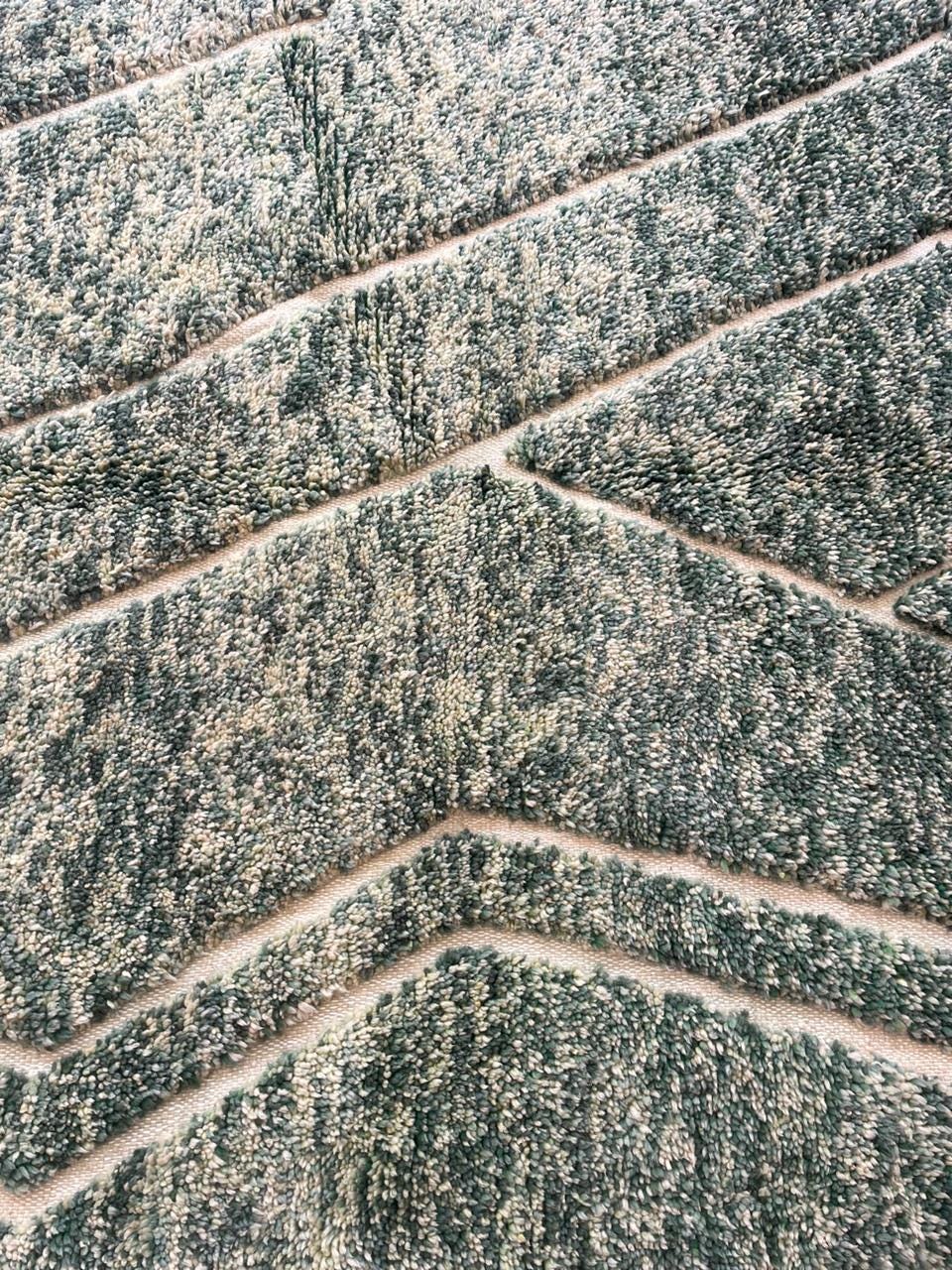Detail shot of a green Moroccan rug highlighting a zigzag pattern.