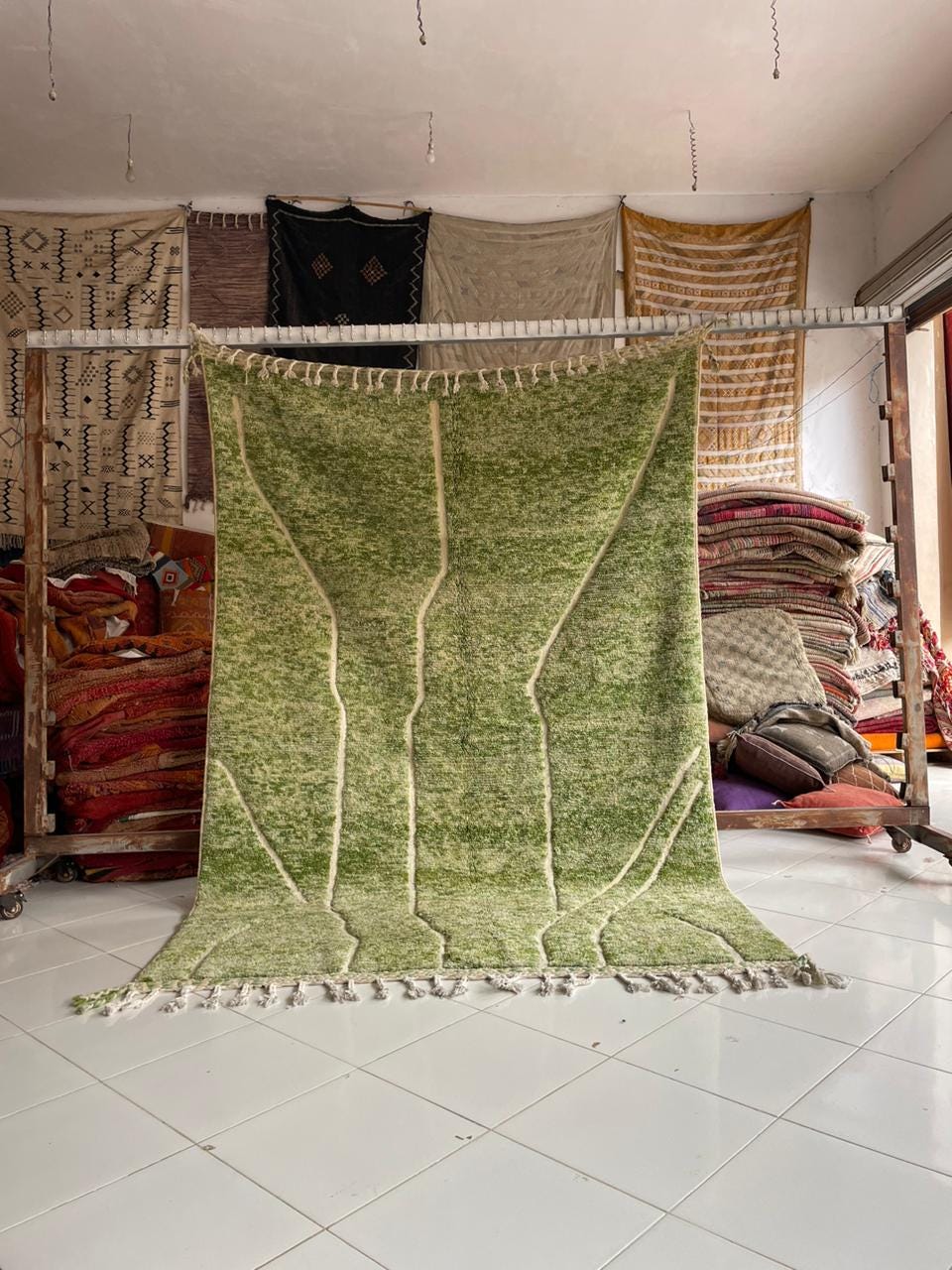 Lifestyle shot of a green Moroccan rug with fringe edges on a natural background.