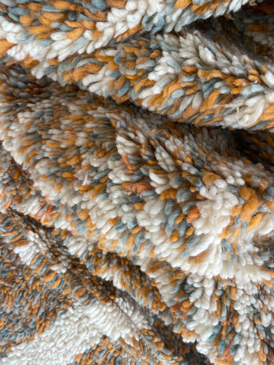 Close-up detail of soft texture on orange, gray, and white Moroccan rug.