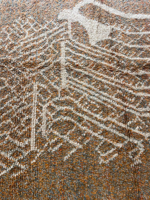 Close-up view of orange, gray, and white Moroccan rug with geometric pattern.