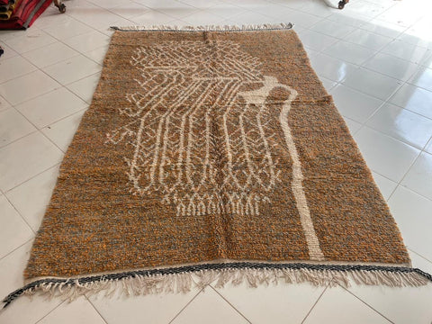 Close-up detail of orange and gray Moroccan rug showcasing fringe edges and textured surface.