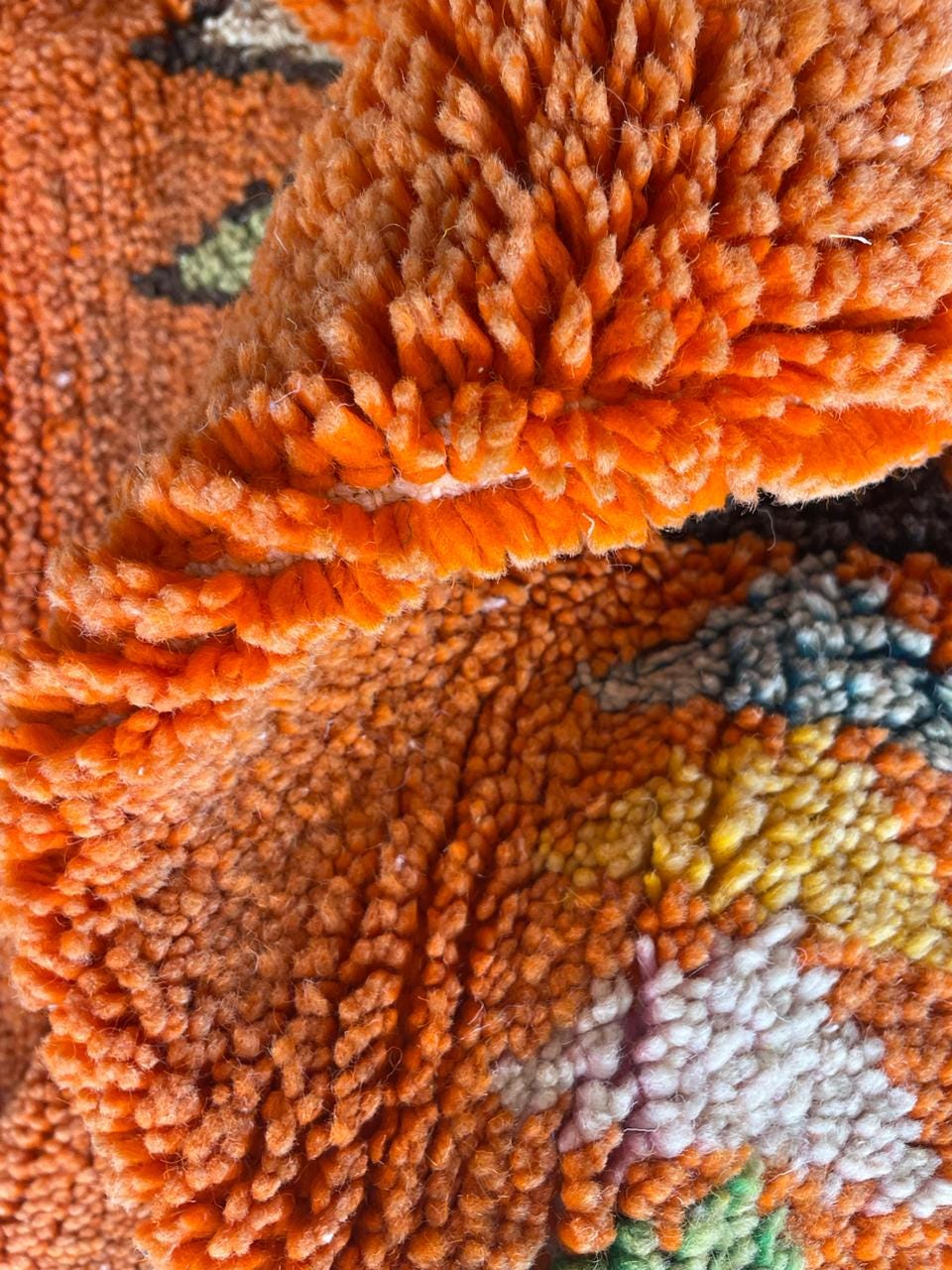 Close-up detail of an orange rug with a textured pattern.
