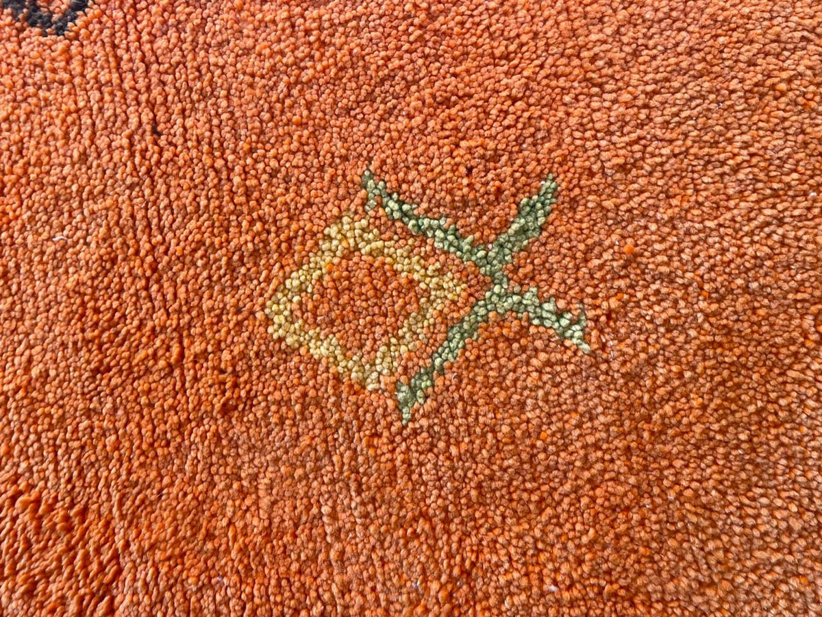 Close-up detail of an orange Moroccan rug showcasing a geometric design.