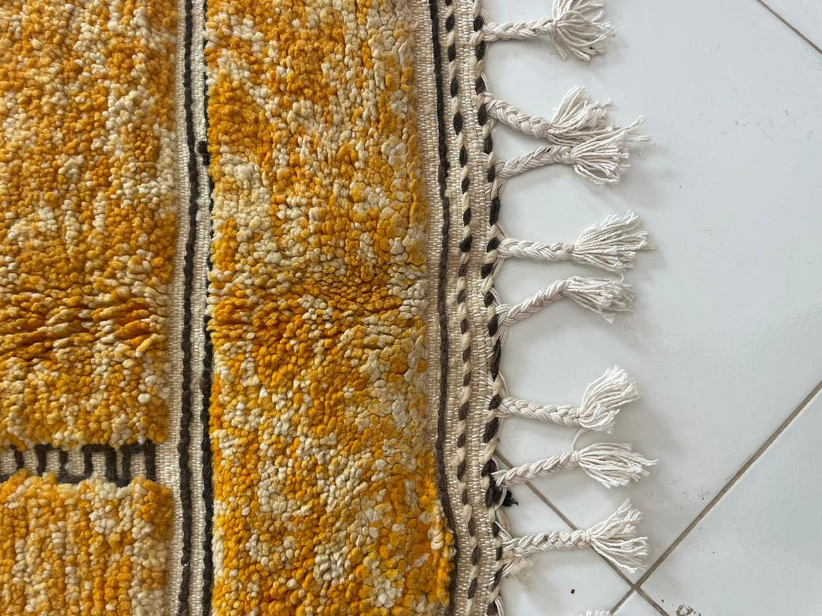 Detail close-up of an orange Moroccan rug showcasing fringe details.