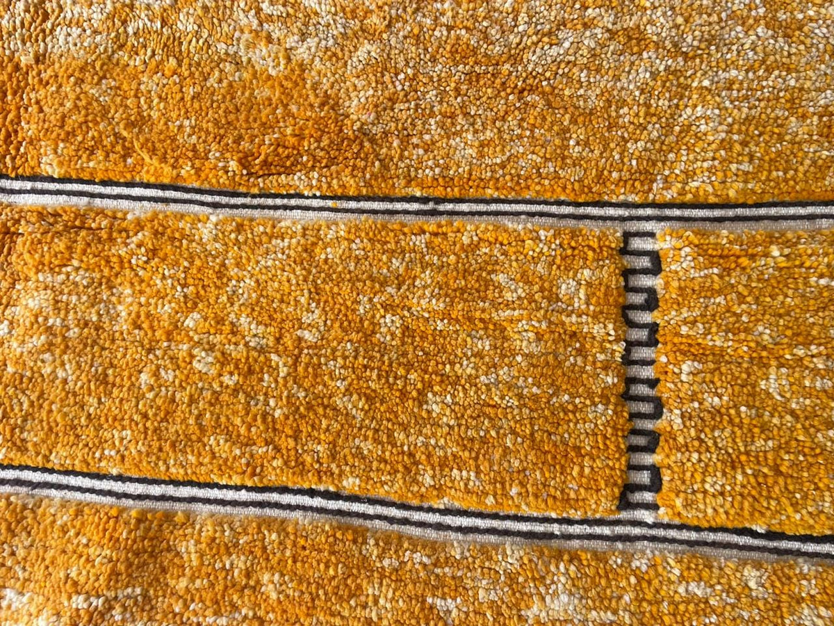 Detail close-up of an orange Moroccan rug with a textured design.