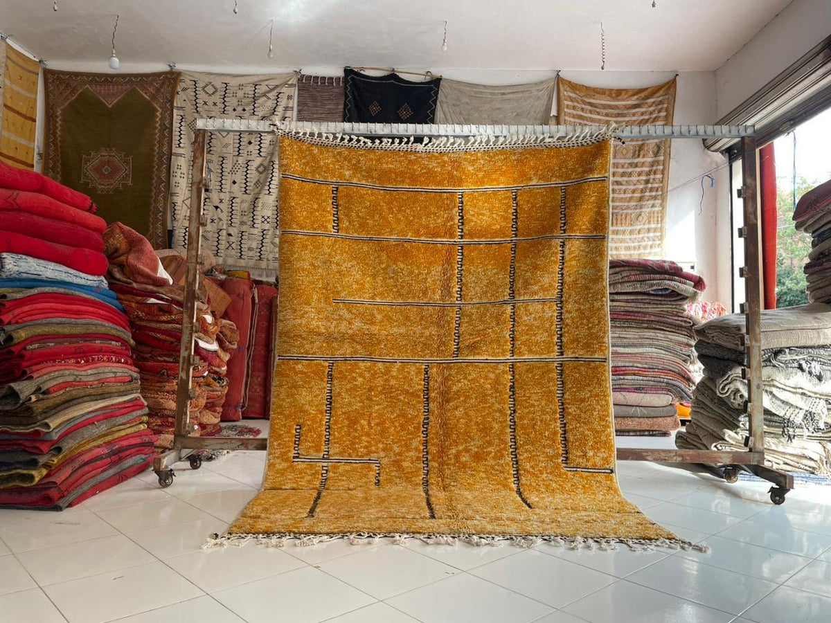 Lifestyle shot of an orange Moroccan rug with geometric patterns in a natural setting.