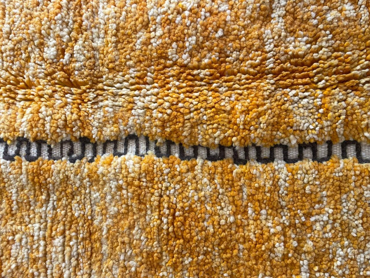 Detail close-up of an orange Moroccan rug emphasizing its textured pattern.