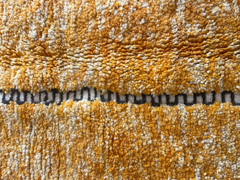 Detail close-up of an orange Moroccan rug emphasizing its textured pattern.