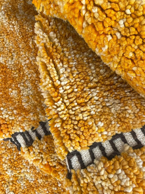 Detail close-up of an orange Moroccan rug with a textured design.
