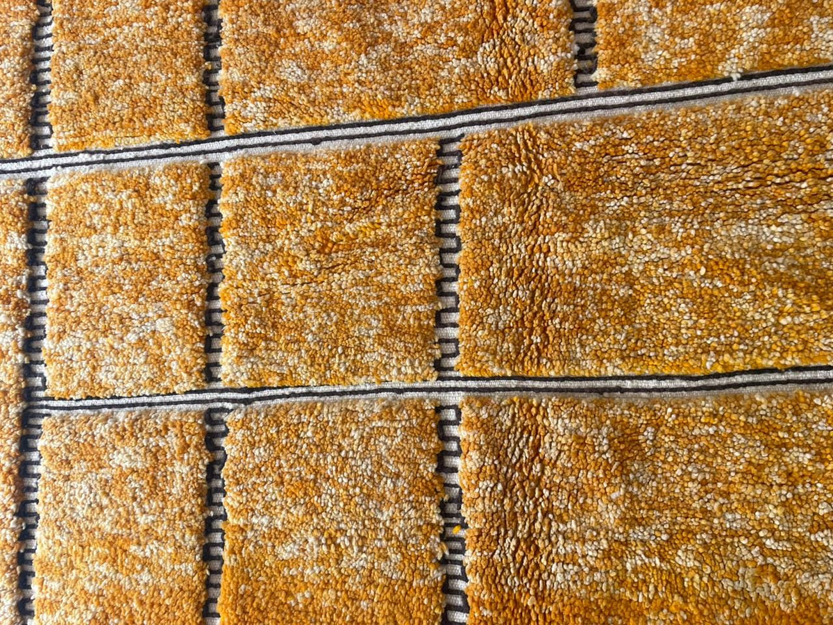 Detail close-up of an orange Moroccan rug highlighting its geometric pattern.