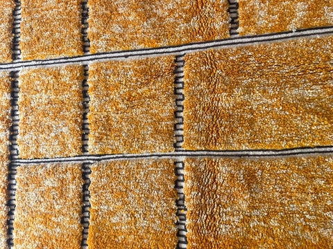 Detail close-up of an orange Moroccan rug highlighting its geometric pattern.