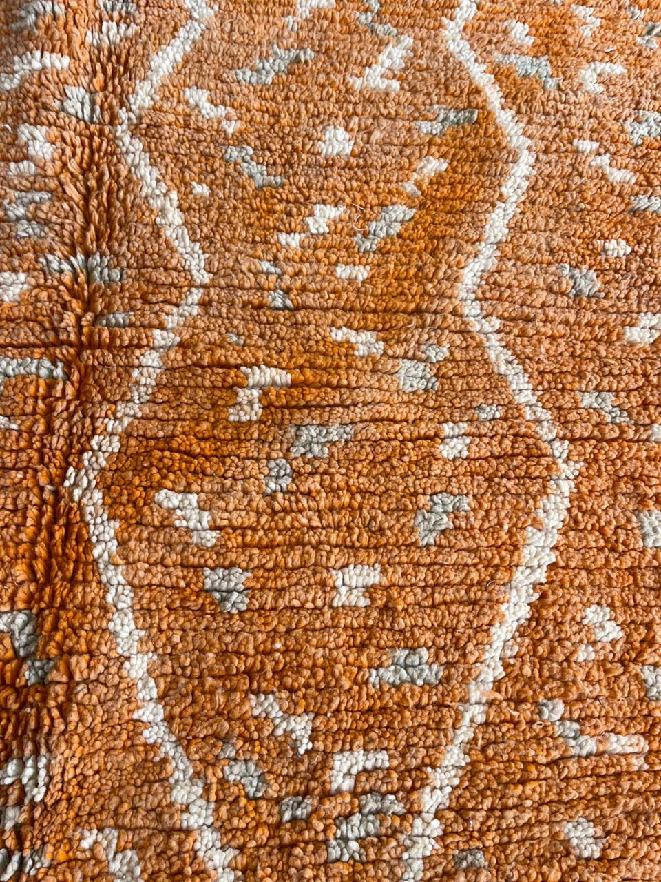 Top view showcasing the orange Moroccan rug with geometric patterns and fringe edges.