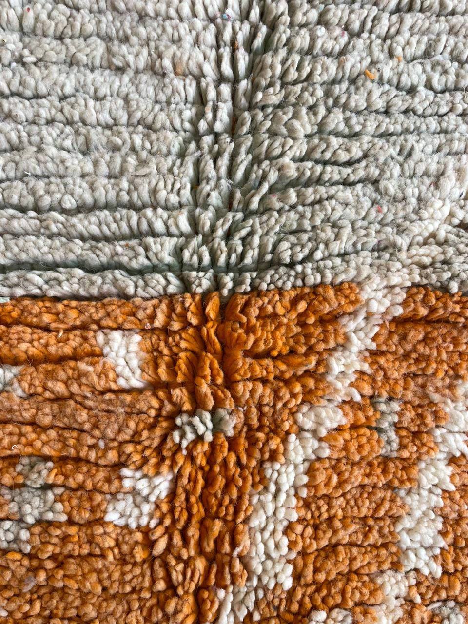 Detail close-up of the textured weave and geometric pattern of the orange rug.