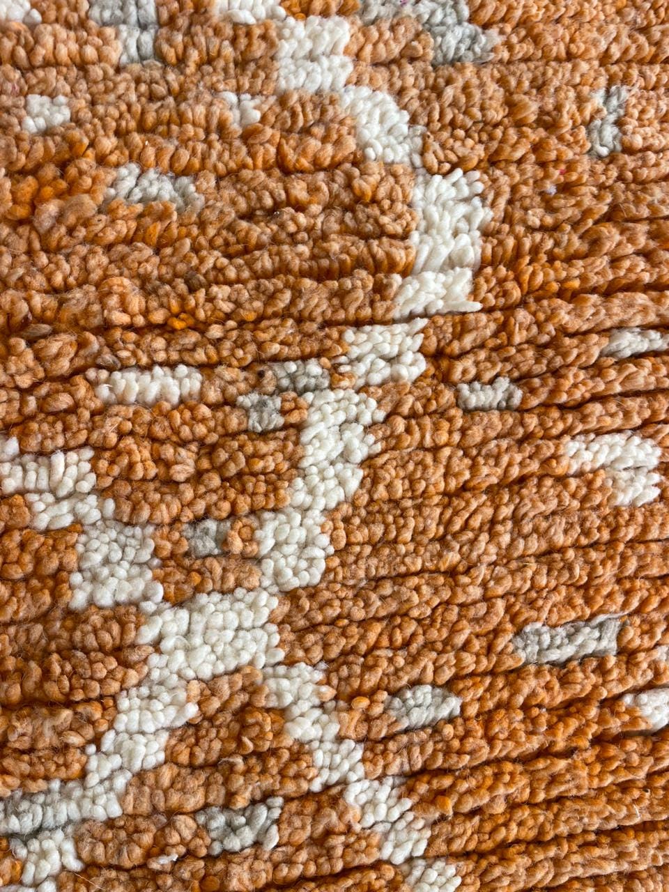 Detail shot highlighting the textured weave and geometric pattern of the orange rug.