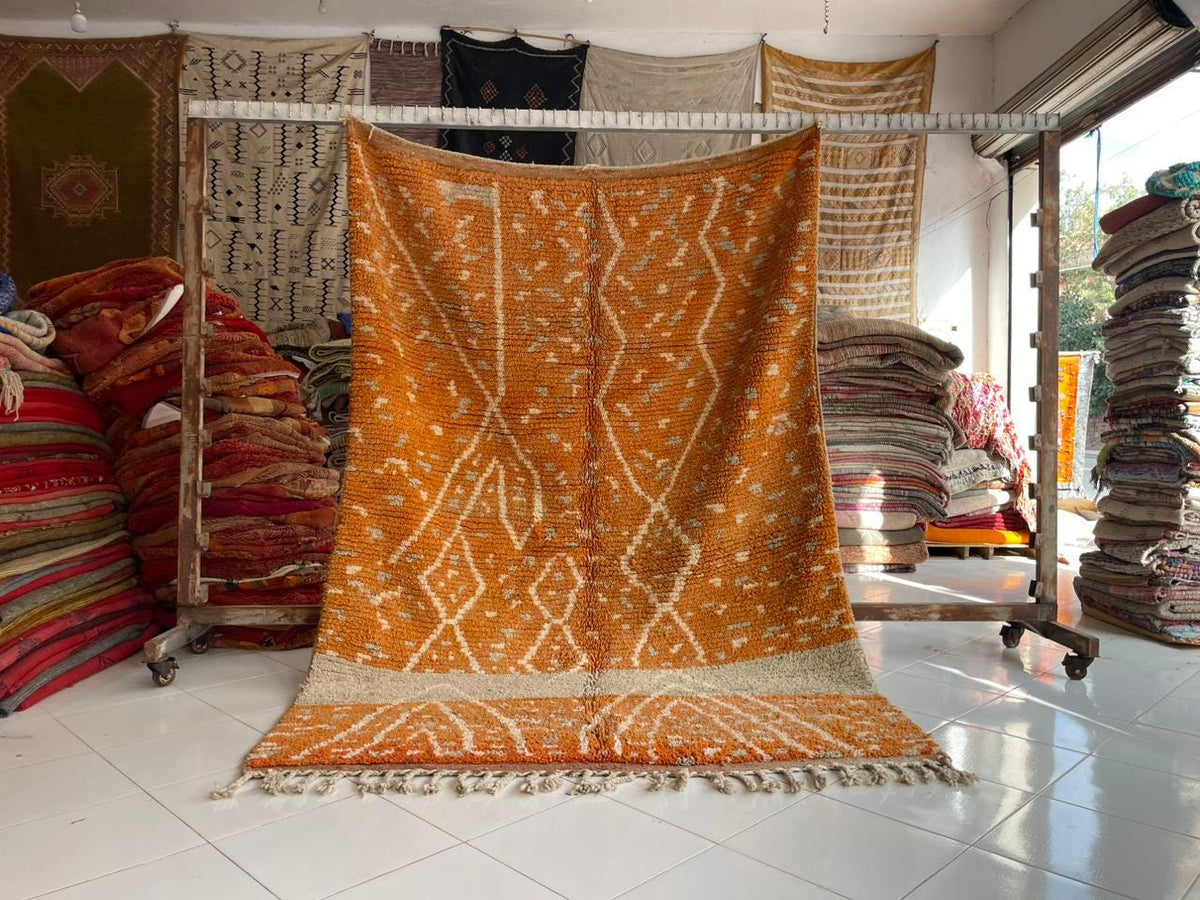Lifestyle shot of a large orange rug featuring geometric design in a studio setting.