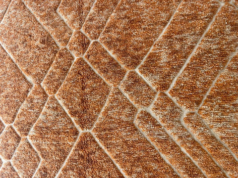 Close-up detail of an orange Moroccan rug showcasing a geometric design and soft texture.