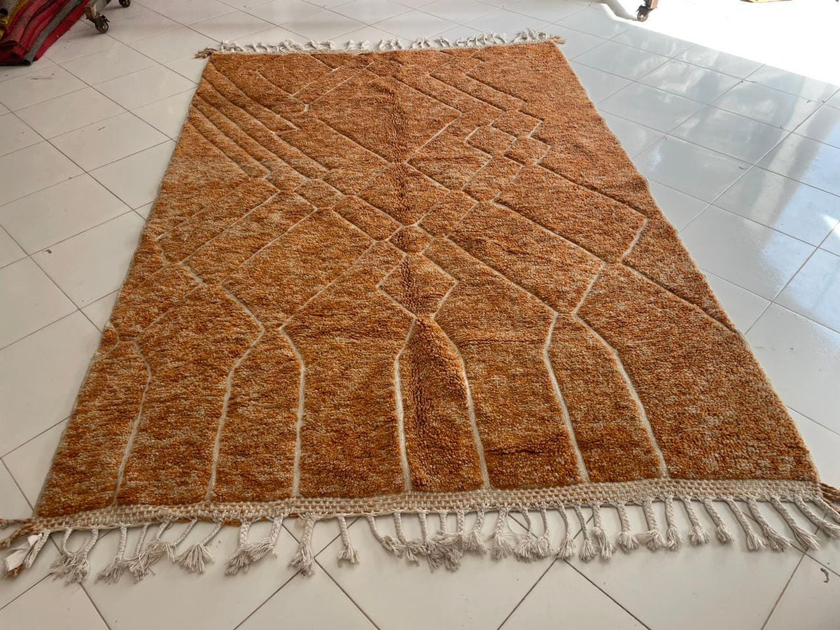 Front view of an orange Moroccan rug featuring fringe edges against a white background.