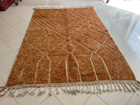 Front view of an orange Moroccan rug featuring fringe edges against a white background.