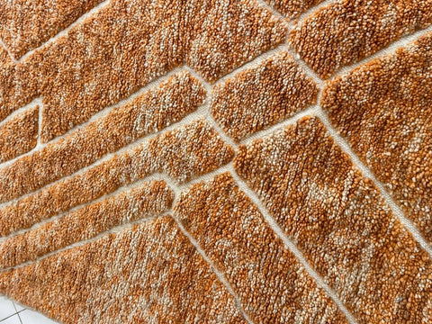 Detail shot of an orange Moroccan rug highlighting its textured surface and patterned weave.