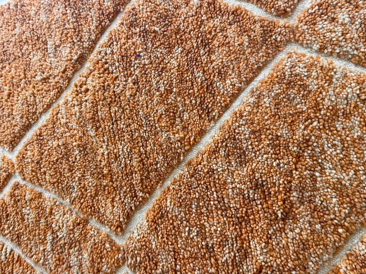 Close-up of an orange Moroccan rug emphasizing its textured surface.