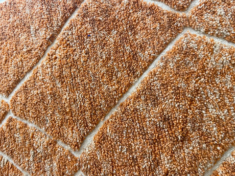 Close-up of an orange Moroccan rug emphasizing its textured surface.