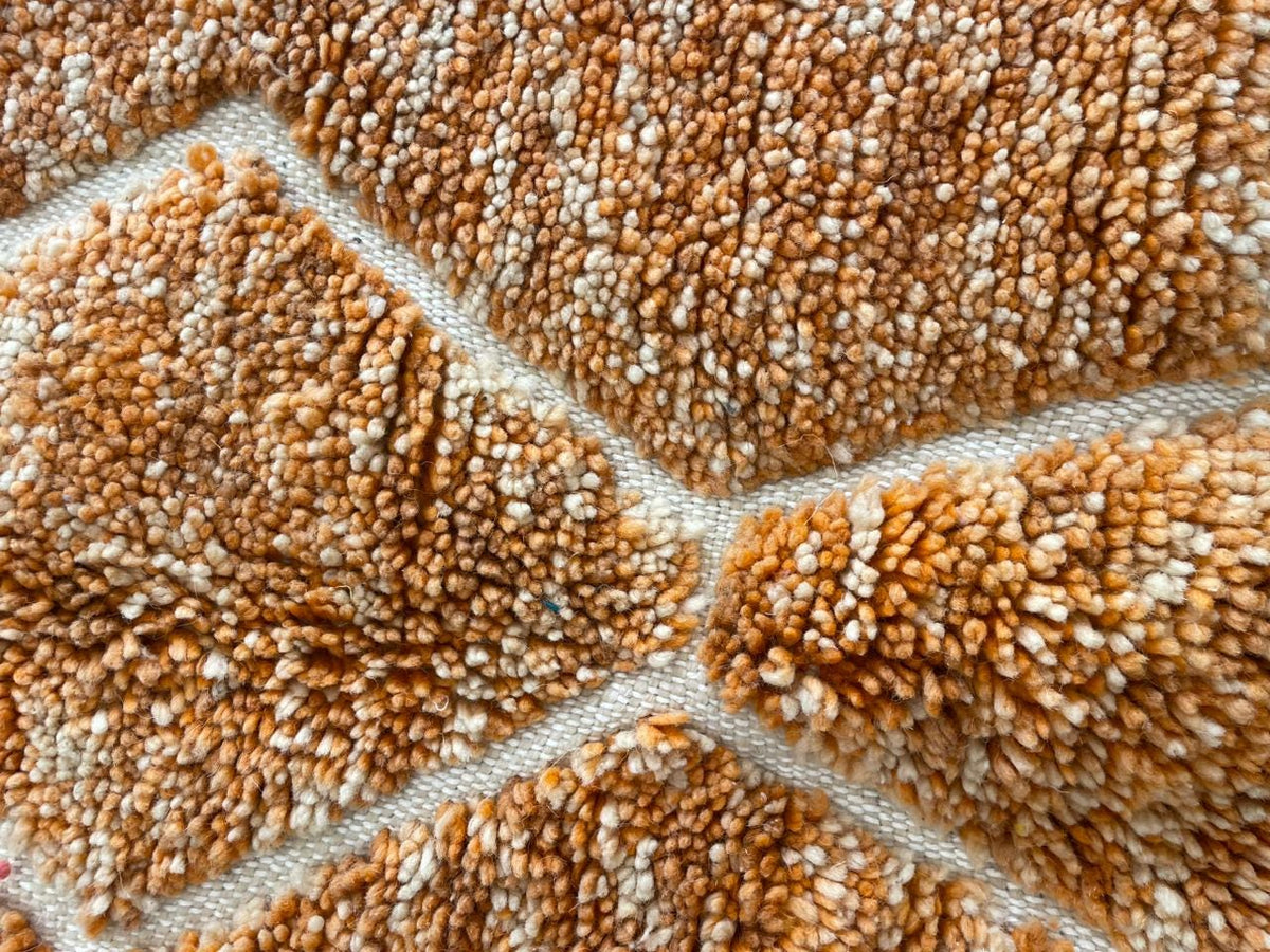 Close-up detail of an orange Moroccan rug showcasing its textured surface.