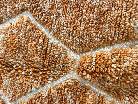 Close-up detail of an orange Moroccan rug showcasing its textured surface.