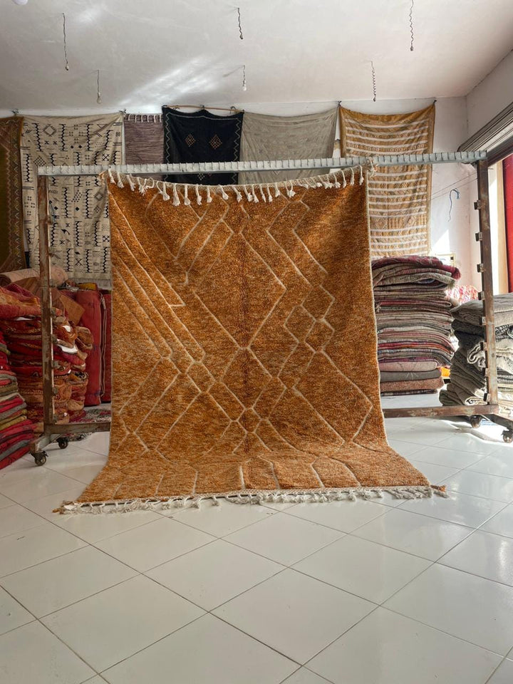 Lifestyle shot of an orange Moroccan rug with geometric patterns on a natural background.