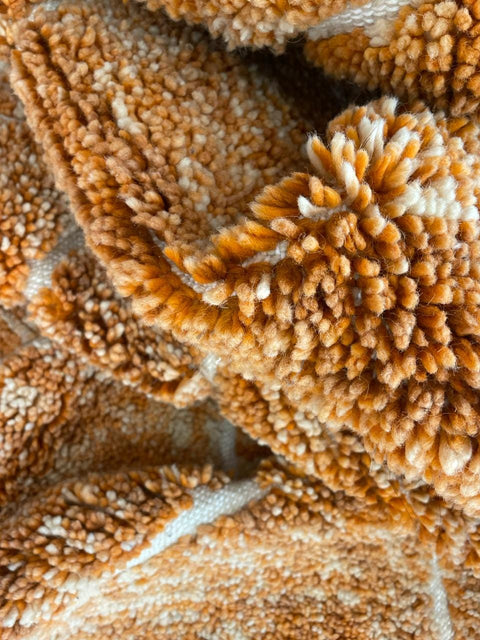 Close-up view of an orange Moroccan rug highlighting its textured surface.