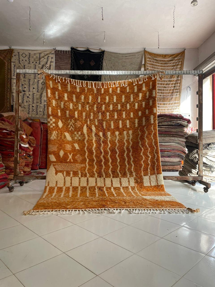 Lifestyle view of the orange Moroccan rug with geometric patterns on a natural background.