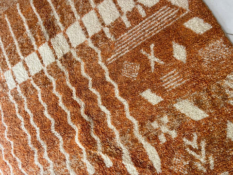 Close-up detail of the orange Moroccan rug featuring a patterned design.