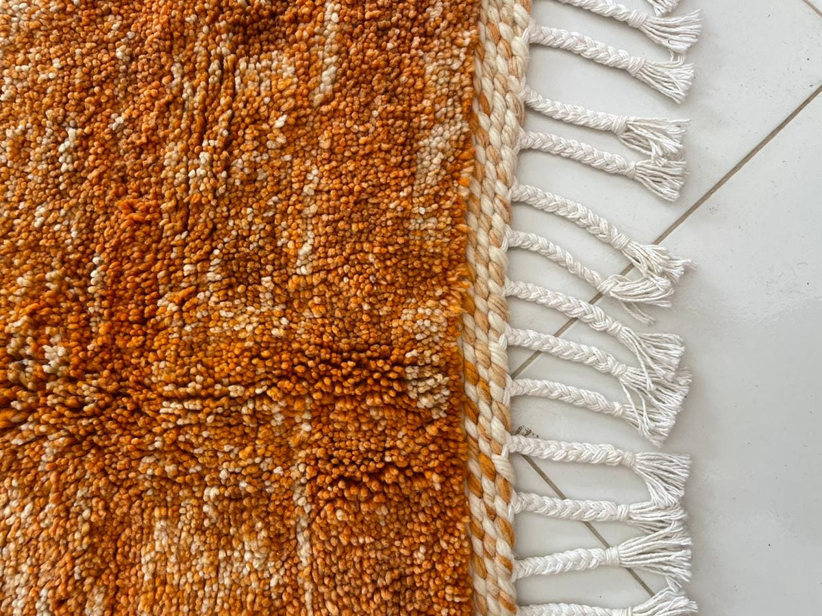 Close-up detail of the orange rug with a textured surface against a white background.