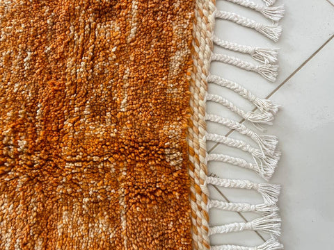 Close-up detail of the orange rug with a textured surface against a white background.