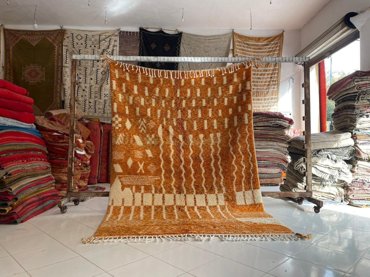 Lifestyle view of the orange rug with a woven pattern displayed in a natural setting.
