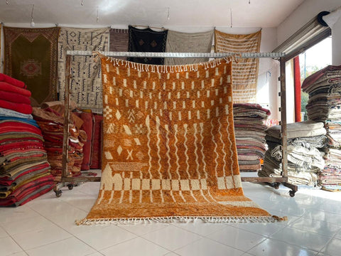 Lifestyle view of the orange rug with a woven pattern displayed in a natural setting.