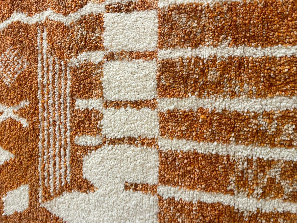 Close-up detail of the orange and white rug displaying a geometric pattern.