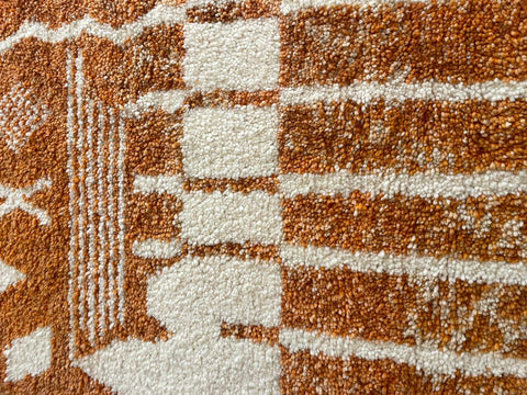 Close-up detail of the orange and white rug displaying a geometric pattern.