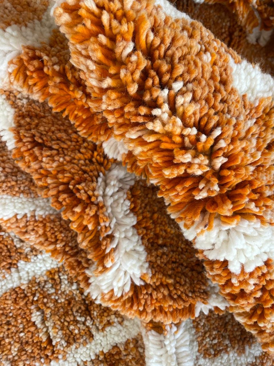 Close-up detail of the orange and white rug with a textured surface and fringe edges.