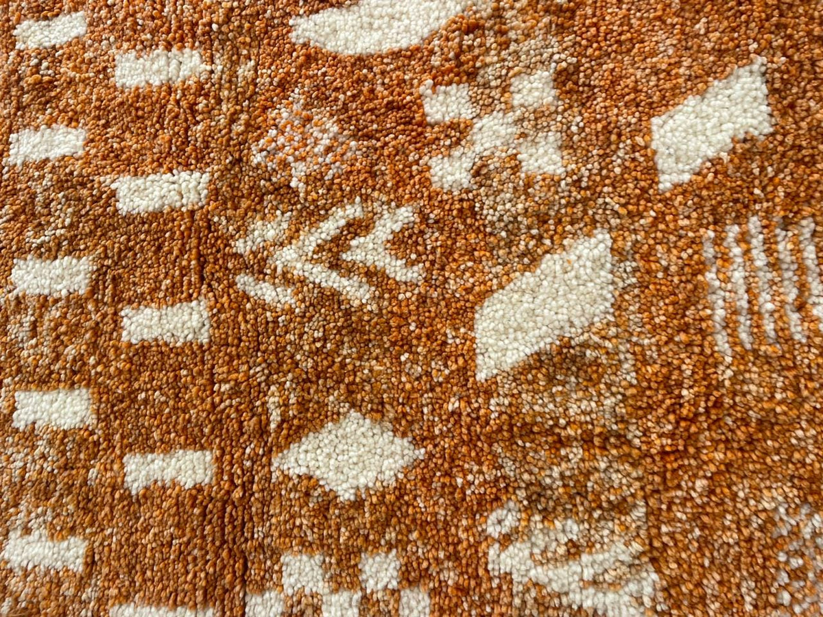 Close-up detail of the orange Moroccan rug with intricate patterns.