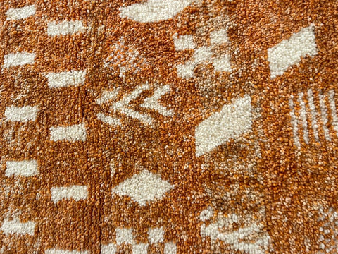 Close-up detail of the orange Moroccan rug with intricate patterns.