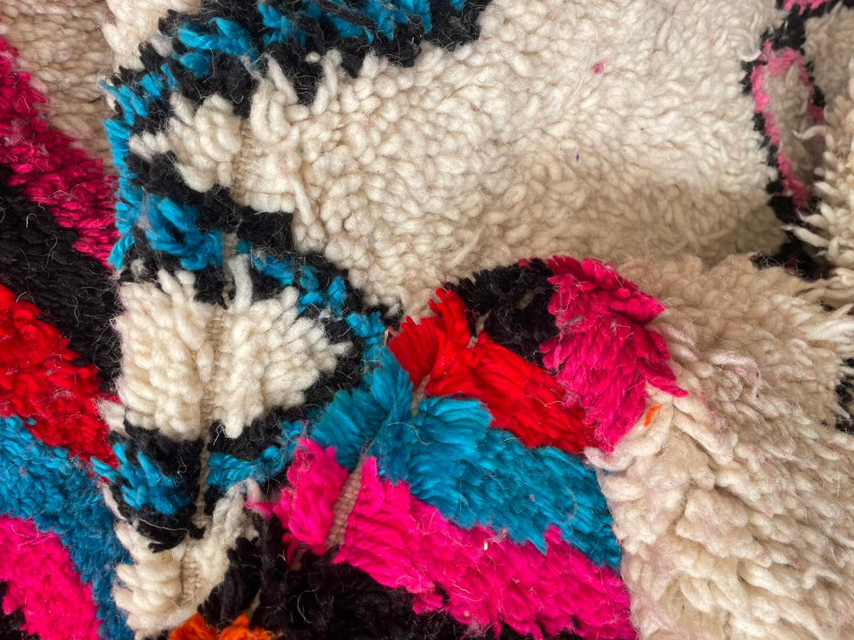 Close-up detail of a colorful pink rug featuring a textured design and vibrant colors.