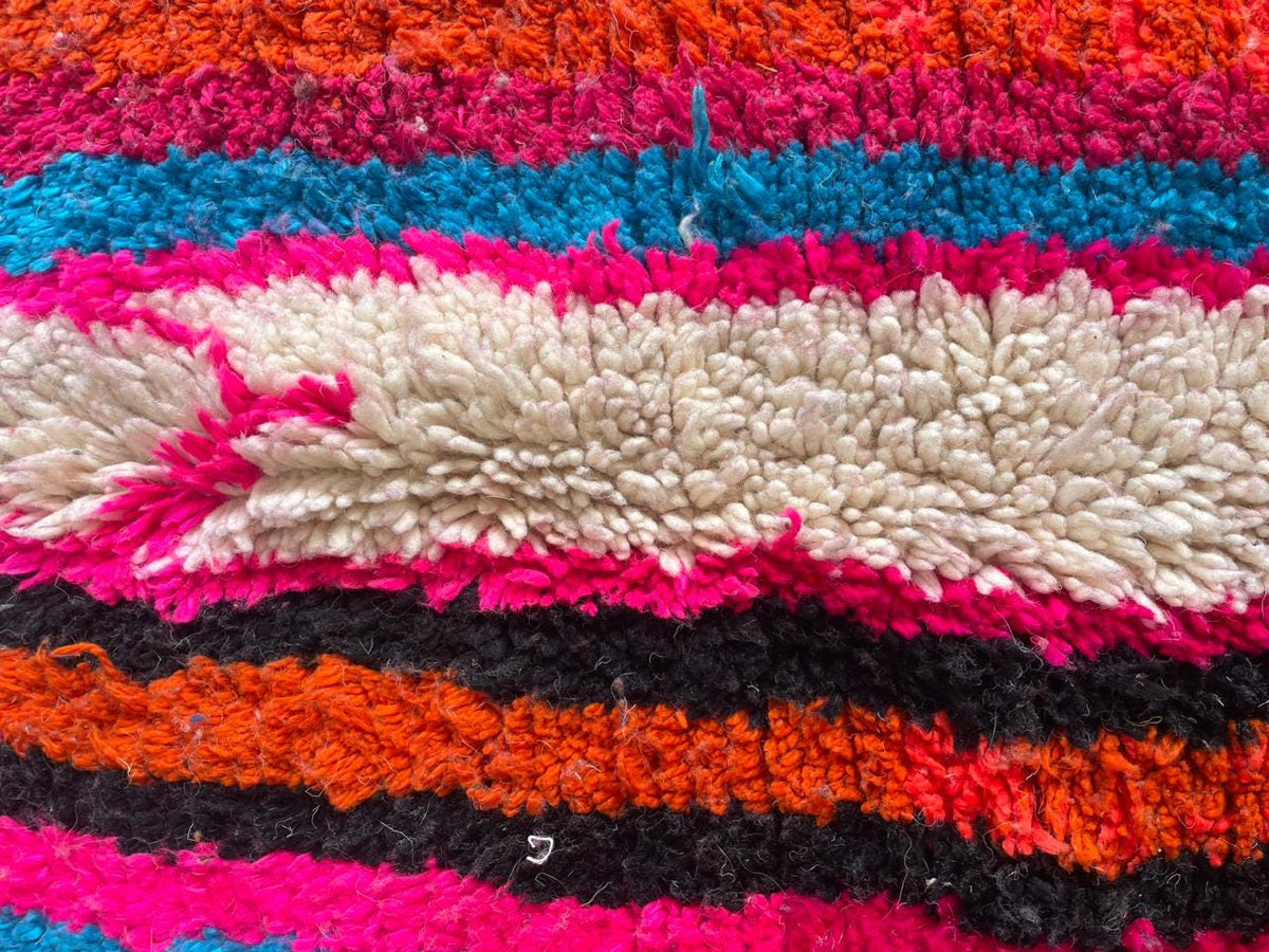 Close-up detail of a colorful pink Moroccan rug with a striped pattern.